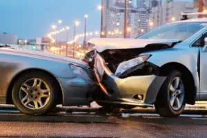 Two cars involved in a front-end collision on a city street, both vehicles showing significant damage to their front ends.