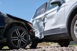 A black car has collided with the side of a white SUV, causing visible damage to both vehicles.