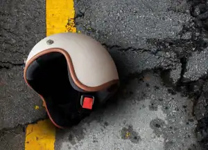 A motorcycle helmet lies on cracked asphalt near a yellow line.